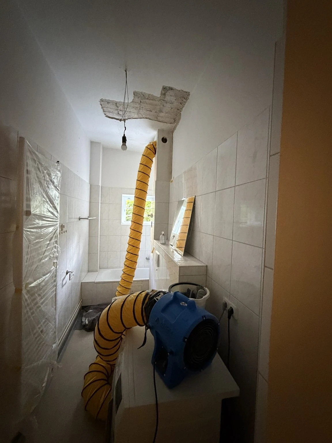 Schachttrocknung mit Lüfter und orangefarbenem Luftschlauch am geöffneten Schacht
